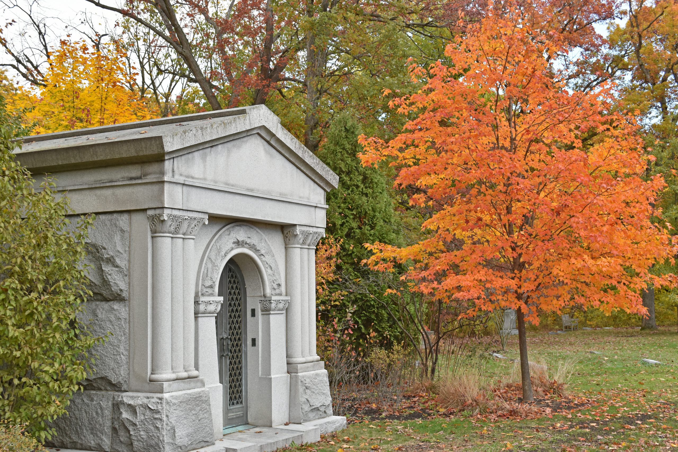 A white stone mausoleum sits amidst the orange and yellow autumn trees A white stone mausoleum sits amidst the orange and yellow autumn trees